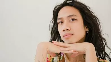 headshot of someone with long dark hair and a floral shirt
